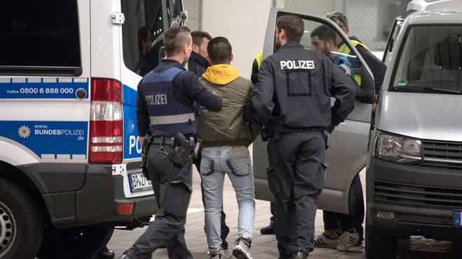 Justiz: Ein junger Mann aus Afghanistan trägt Handschellen und Fußfesseln und die Polizei bringt ihn zur Abschiebung zum Flughafen.