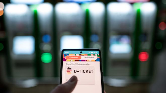 Nahverkehr: Ein Mann hält ein Mobiltelefon in der Hand, auf dem das „D-Ticket“ gekauft werden kann.