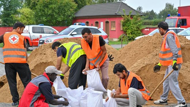 Hochwassergefahr: Nach einem Aufruf zur freiwilligen Hilfe arbeiten Mitarbeiter einer Unterkunft der Zentralen Ausländerbehörde an Sandsäcken.