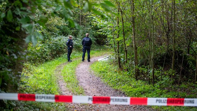 Polizei: Polizisten stehen auf abgesperrten Waldweg.