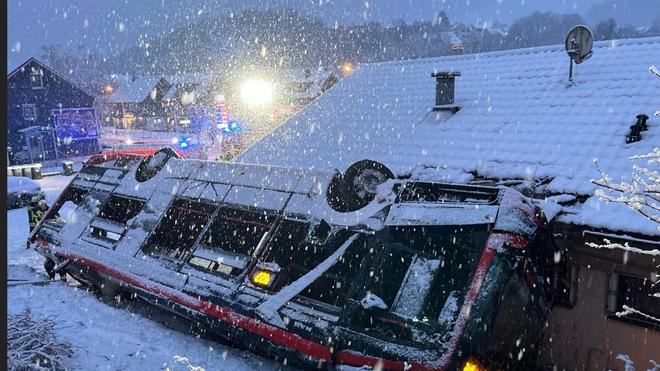 Glätteunfall: Weil sich der Bus mit dem Dach verkeilt hat, ist es für die Rettungskräfte aufwendig, ihn zu bergen.