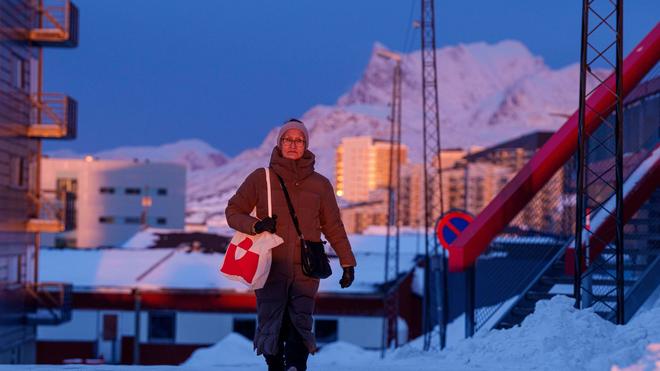 Fotografie: Eine Frau geht bei Sonnenuntergang auf einer Straße in Nuuk.