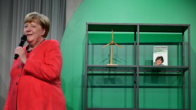 Fotografie: Angela Merkel (CDU), Bundeskanzlerin a.D. und ehemalige Bundesumweltministerin, spricht auf der Bühne beim Festakt «Seit 40 Jahren NaturVerbunden» zum 40. Jubiläum des Bundesumweltministeriums im Café «Moskau», während im Hintergrund ihr Buch mit dem Titel „Der Preis des Überlebens“ zu sehen ist.
