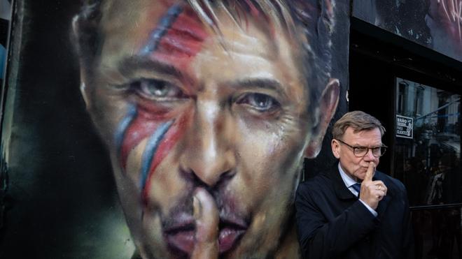 Fotografie: Der deutsche Außenminister Johann Wadephul (CDU) steht bei einem Rundgang durch das Stadtzentrum von Buenos Aires neben einem Graffiti von David Bowie.