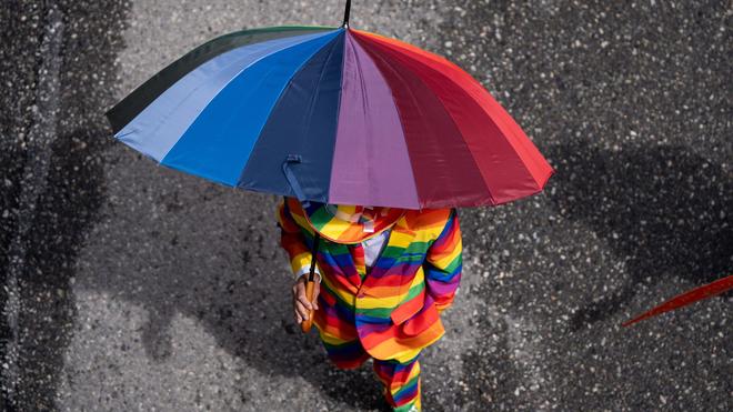 Fotografie: Eine Person in einem Regenbogenanzug nimmt an der Vancouver Pride Parade teil.