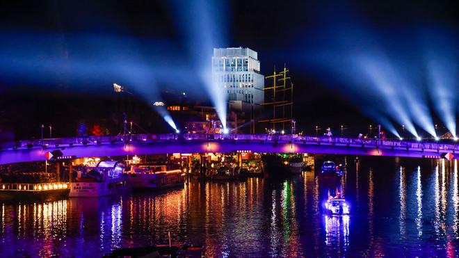 Fotografie: Beleuchtete Boote und Schiffe fahren am Tag der Deutschen Einheit bei einer abendlichen Lichtshow auf der Weser in Bremen.