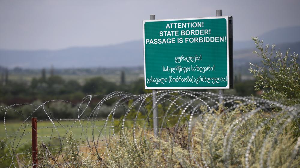 Georgien: Ein von Russland errichtetes Warnschild in Englisch und Georgisch an der Grenze zwischen der abtrünnigen Region Südossetien und Georgien (2015): Hier markiert Stacheldraht die Grenzlinie.