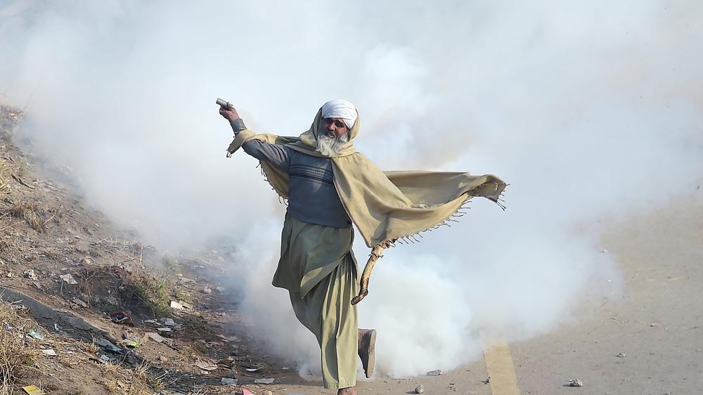 Pakistan: Ein Demonstrant der Gruppe Tehreek Labaik Ya Rasool Allah wirft einen Behälter mit Tränengas in Richtung der Polizei. 