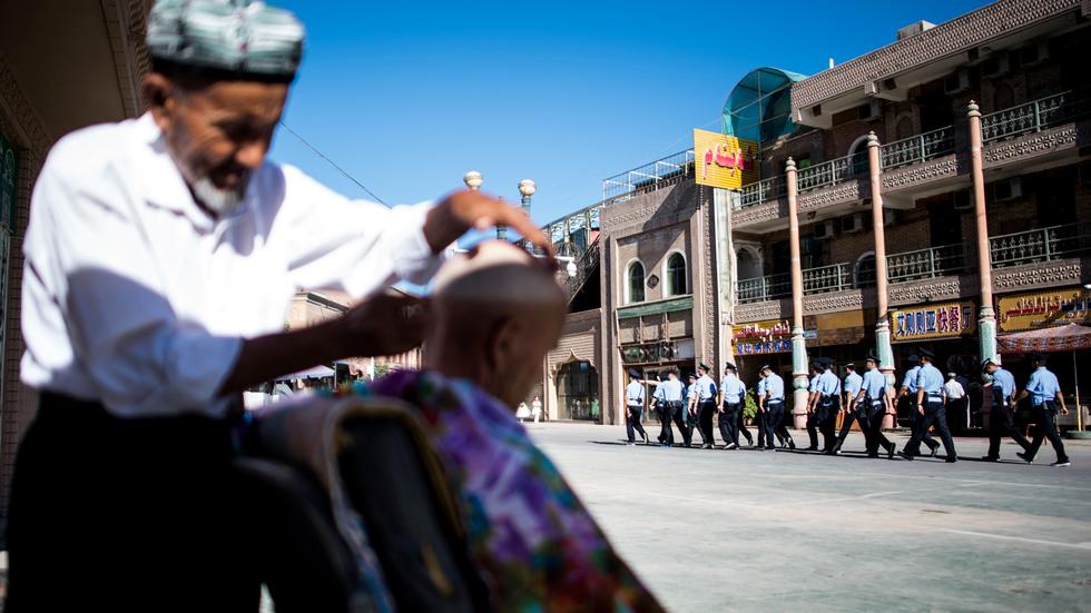 Uiguren: Ein Barbier (vorne) und chinesische Polizisten in der Stadt Kashgar in Xinjiang, Sommer 2017
