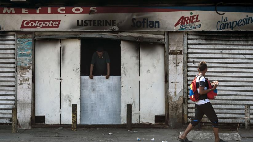 Nicolás Maduro: Ein Passant vor einem der vielen geplünderten Läden in Maracaibo