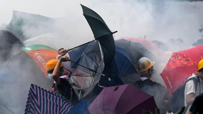 Auslieferungsgesetz: Mit Schirmen schützen sich die Demonstranten gegen die Tränengasattacken der Polizei.