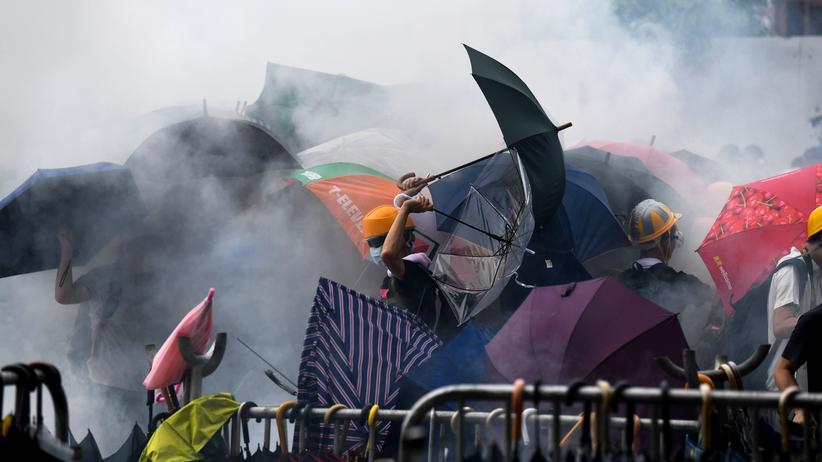 Auslieferungsgesetz: Mit Schirmen schützen sich die Demonstranten gegen die Tränengasattacken der Polizei.