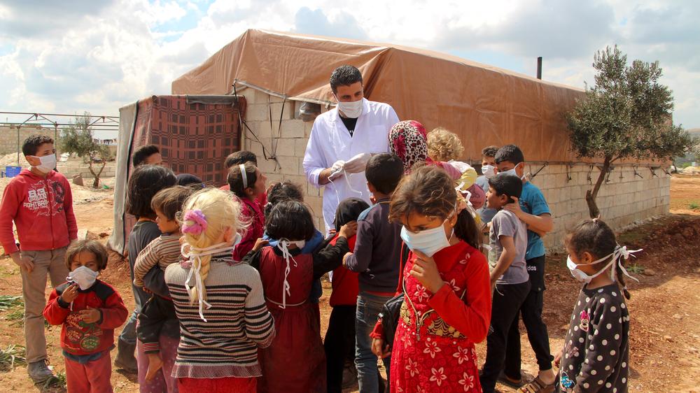 Coronavirus in Syrien: Ein Arzt verteilt Schutzmasken an Kinder in einem Vertriebenenlager nahe der Stadt Batabu im Nordwesten von Syrien. 