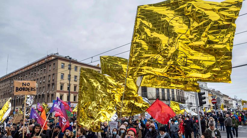 Demonstrierende weisen auf die prekäre Lage an der polnisch-belarussischen Grenze hin. Geflüchtete drohten zu erfrieren, heißt es. Aus Solidarität schwingen die Protestler Rettungsdecken.