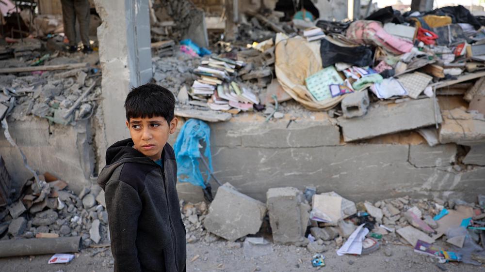 Nahostüberblick: Ein palästinensisches Kind steht vor einem von israelischen Bomben zerstörten Gebäude in Rafah.