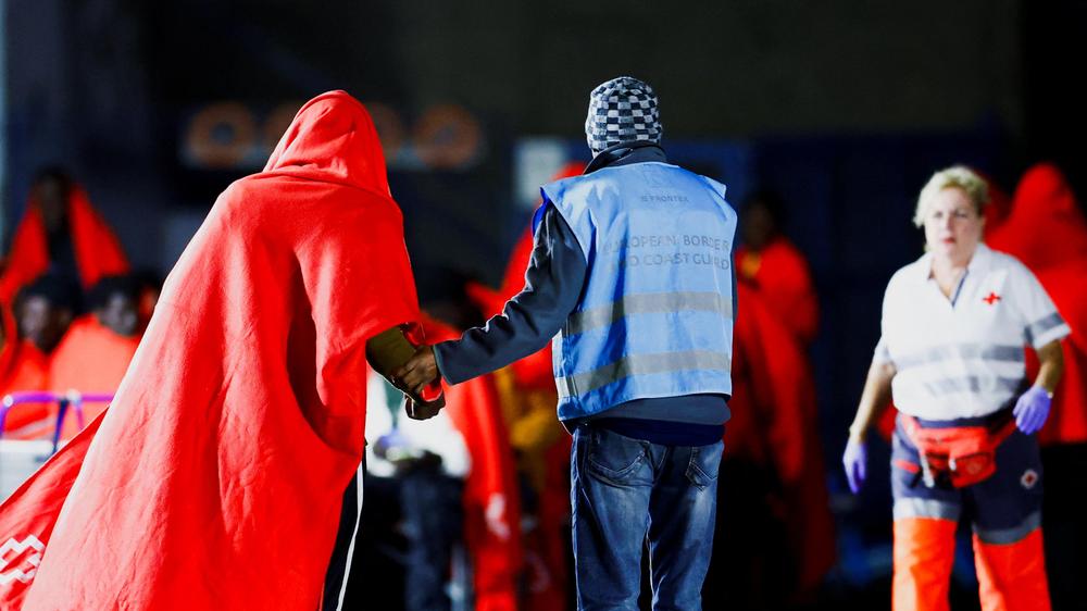  Ein Mitarbeiter der europäischen Grenzschutzbehörde Frontex hilft einem Geflüchteten, den die spanische Küstenwache in Gran Canaria an Land gebracht hat.