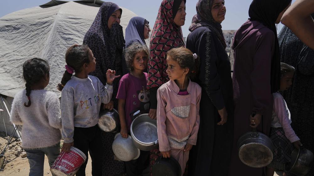  Vertriebene Palästinenser warten in einem Zeltlager in Gaza-Stadt, um gespendete Mahlzeiten aus einer Gemeinschaftsküche zu erhalten.