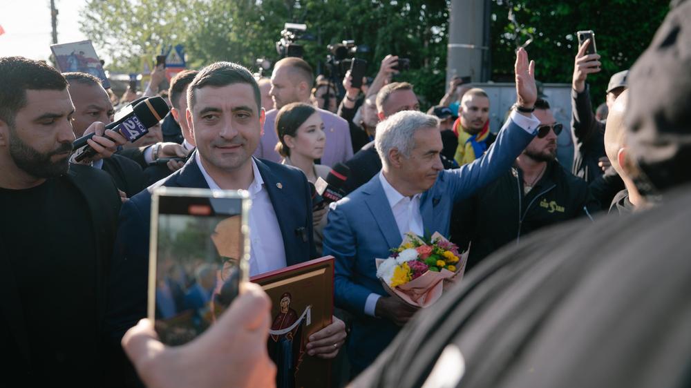  George Simion geht links neben seinem Parteikollegen Călin Georgescu, der wegen illegaler russischer Einflussnahme von der Präsidentschaftswahl in Rumänen ausgeschlossen worden war.