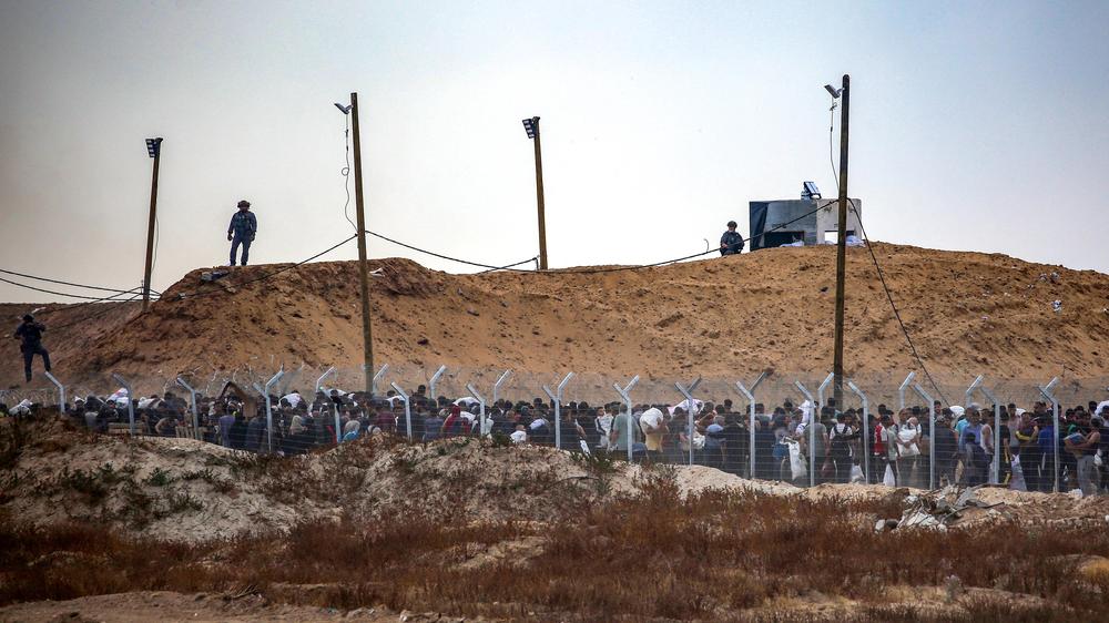  Members of a private US security company, contracted by the Gaza Humanitarian Foundation (GHF), a private US-backed aid group which the UN refuses to work with over neutrality concerns, direct displaced Palestinians as they gather to receive relief supplies at a distribution centre in the central Gaza Strip on June 8, 2025. (Photo by Eyad BABA / AFP) (Photo by EYAD BABA/AFP via Getty Images)