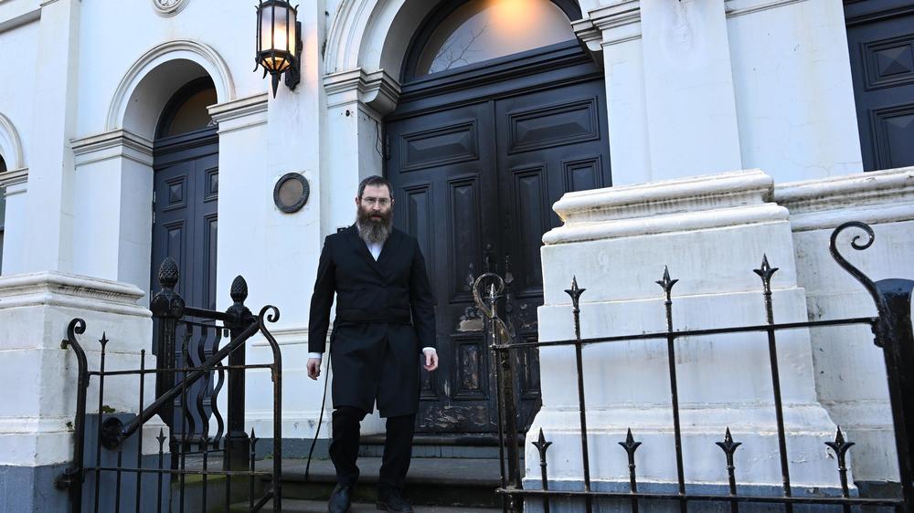  Rabbiner Dovid Gutnick vor der durch einen Brandanschlag beschädigten Tür der Synagoge der East Melbourne Hebrew Congregation in Melbourne.