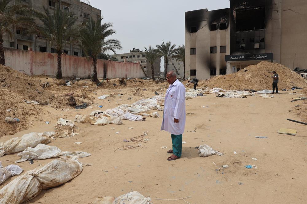 Israelische Angriffe auf Gaza: TOPSHOT - A doctor stands near bodies lined up for identification after they were unearthed from a mass grave found in the Nasser Medical Complex in the southern Gaza Strip on April 25, 2024, amid the ongoing conflict between Israel and the Palestinian militant group Hamas. The head of Gaza's Civil Defence agency in Khan Yunis, raised to 392 the number of bodies he said had been recovered from three mass graves at the city's Nasser Medical Complex. (Photo by AFP) (Photo by -/AFP via Getty Images)