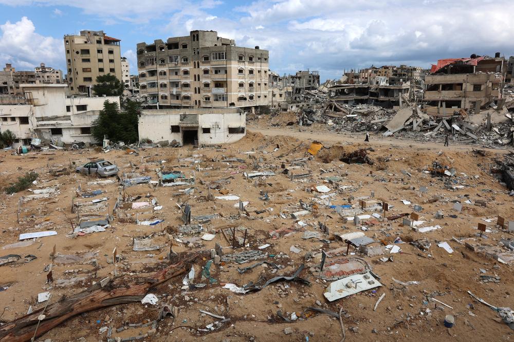 Israelische Angriffe auf Gaza: People walk past makeshift graves on the ground outside the destroyed al-Shifa hospital in Gaza City on September 17, 2024, amid the ongoing war between Israel and the Palestinian Hamas group. Once the crown jewel of Gaza's proud medical community, the Palestinian territory's main Al-Shifa hospital has become a stark symbol of the utter devastation wrought by the Israel-Hamas war. (Photo by Omar AL-QATTAA / AFP) (Photo by OMAR AL-QATTAA/AFP via Getty Images)