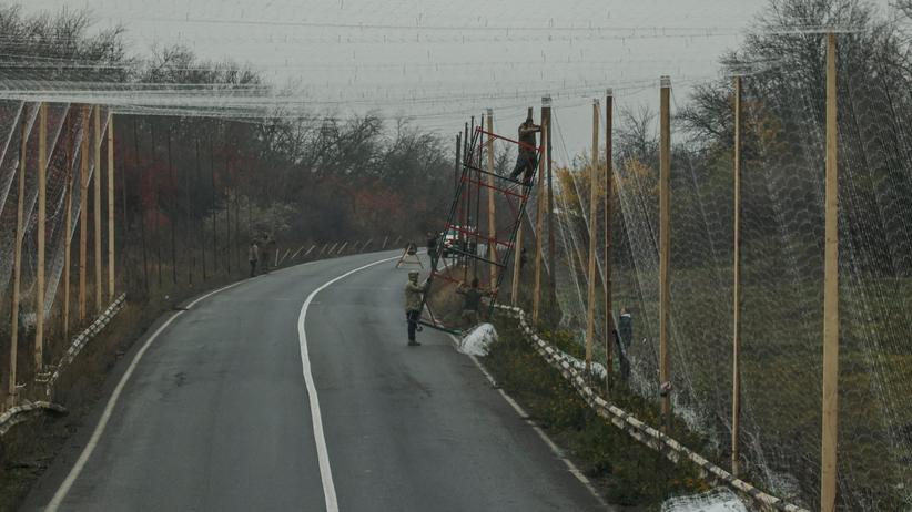 Lage in der Ukraine: Eine Straße im Norden der ostukrainischen Region Donezk: Ukrainische Einsatzkräfte installieren Netze zum Schutz gegen Drohnen.
