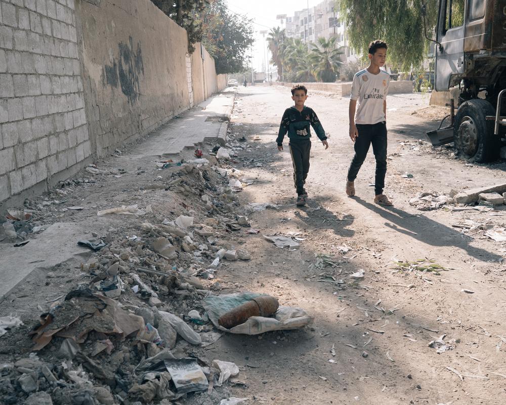 Syrien: Boys walk by an unexploded mortar shell found by a local resident in Harasta.