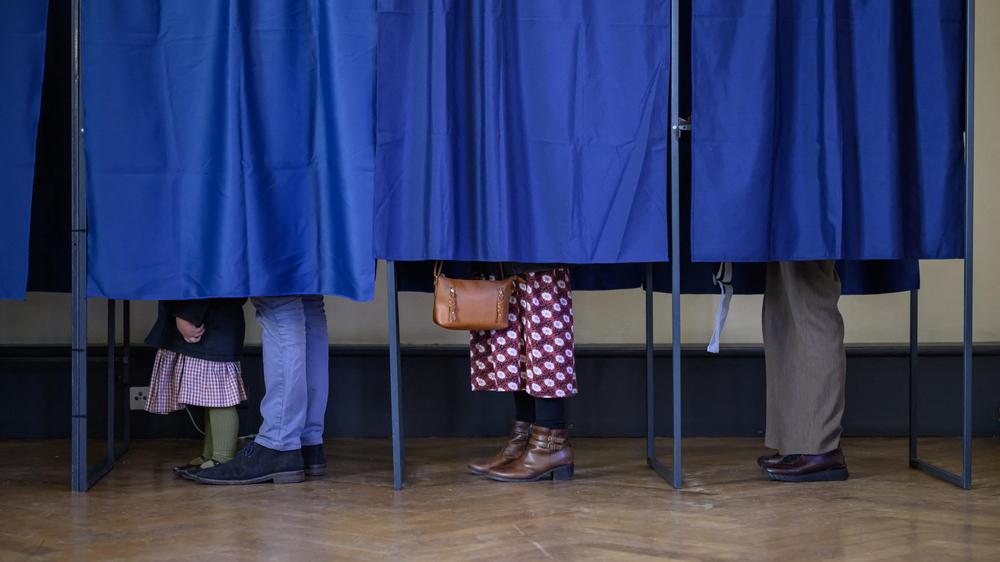  Wählerinnen und Wähler stehen am 15. März in Perpignan in Wahlkabinen.