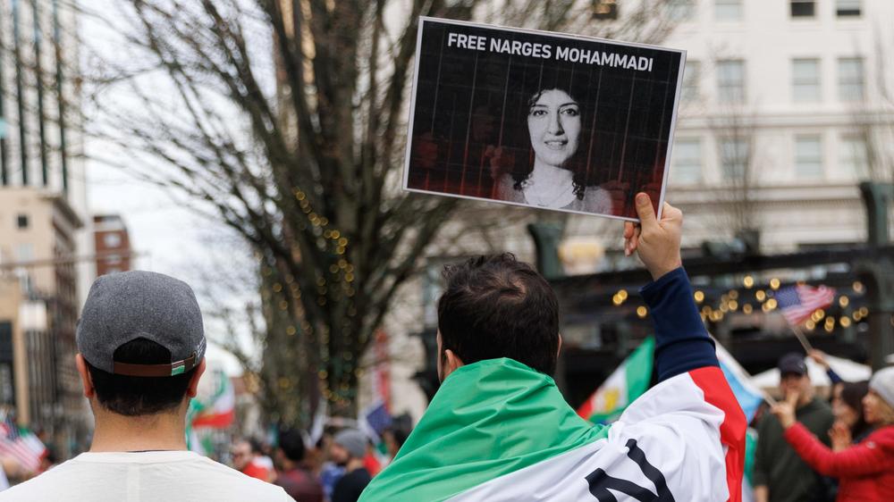  Bei einer Demonstration, bei der Menschen Anfang März in Portland in den USA den Tod von Khamenei feierten, erinnern Teilnehmer an das Schicksal der inhaftierten Friedensnobelpreisträgerin Narges Mohammadi.