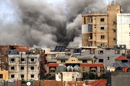 Naher Osten: TOPSHOT - Smoke rises behind buildings following an Israeli airstrike in the southern city of Tyre on May 15, 2026. Israel carried out new strikes in southern Lebanon that it said targeted the militant group Hezbollah on May 15, hours before the two countries' envoys were set to meet for a second day of peace talks in Washington. (Photo by KAWANT HAJU / AFP via Getty Images)