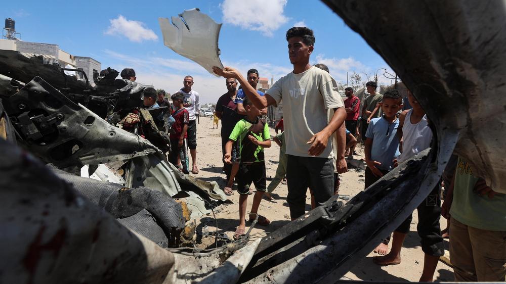  Palästinenser untersuchen in Khan Yunis im südlichen Gazastreifen den Ort eines israelischen Angriffs auf ein Fahrzeug.