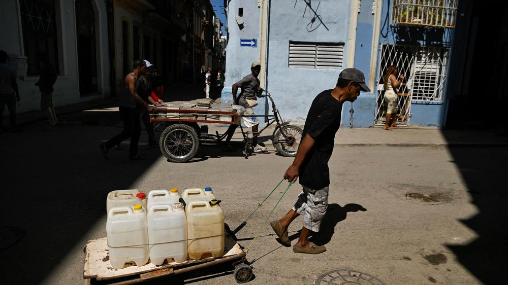  Die Lebensbedingungen in Kuba sind durch die Energieknappheit noch schwieriger geworden; in Havana zieht ein Mann Wassercontainer durch die Straße.