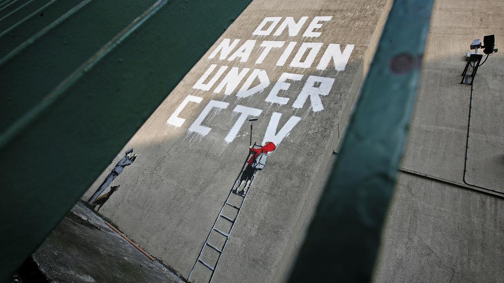 Theresa May: Der Graffitikünstler Banksy hat eine Hauswand in London bemalt: "Eine Nation unter Videoüberwachung" schreibt ein kleines Kind, das dabei von einem Wachmann beobachtet wird.