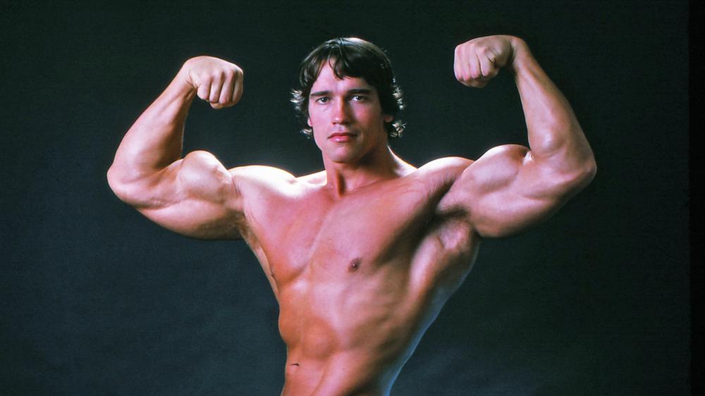 Arnold Schwarzenegger flexing his muscles in 1976