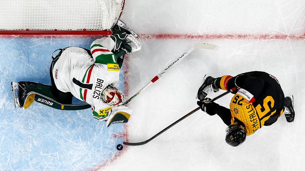 Eishockey-Weltmeisterschaft: Deutschlands Samuel Dove-McFalls (rechts) schießt den Puck gegen Ungarns Torhüter Bence Bálizs.