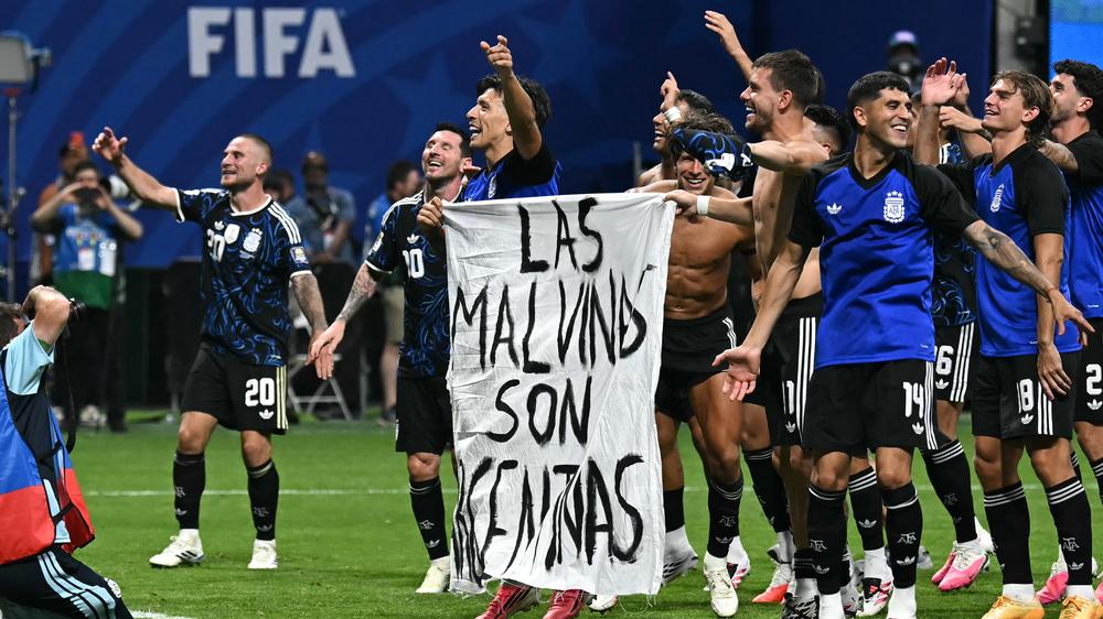  Spieler Argentiniens halten ein Transparent mit der Aufschrift »Las Malvinas son Argentinas« in die Höhe.