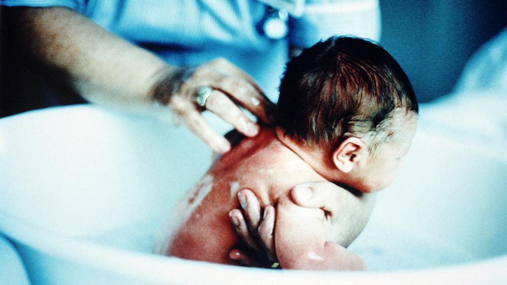 Hebammen: Eine Hebamme badet ein Neugeborenes in einem Krankenhaus.