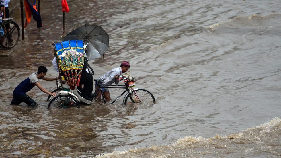 Brot für die Welt: Ein Rikscha-Fahrer in Dhaka zieht sein Gefährt mit Fahrgast durch die Flut – aufgenommen am 26. Juli 2017.