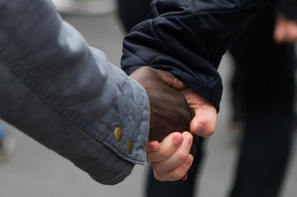 Eine schwarze und weiße Person geben sich die Hand.