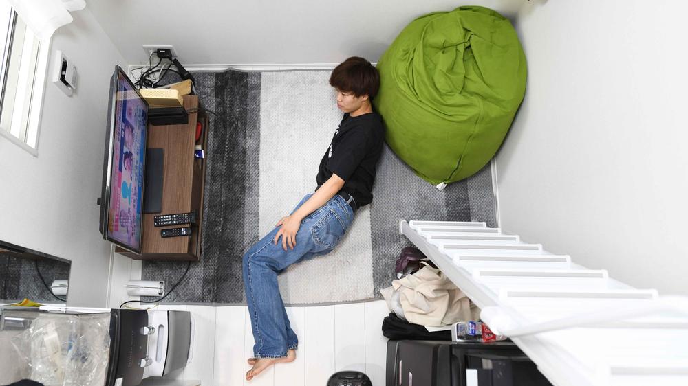 Wohnen in Japan: Yugo Kinoshita watches TV in his apartment in Tokyo, Japan on Thursday, September 15, 2022. New apartments -- known a​s three-tatami rooms, based on​ how many standard Japanese floor mats would cover the living space -- are pushing the boundaries of normal living.