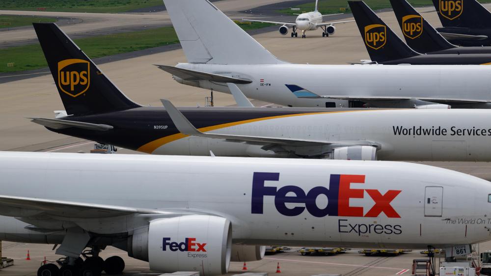   Ein Passagierflugzeug fährt auf dem Flughafen Köln Bonn an den größeren Frachtflugzeugen vorbei.