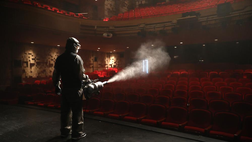 Corona-App: Südkorea im Juli: Im Schutzanzug versprüht ein Seuchenbekämpfer Desinfektionsmittel in einem Theater in Seoul.