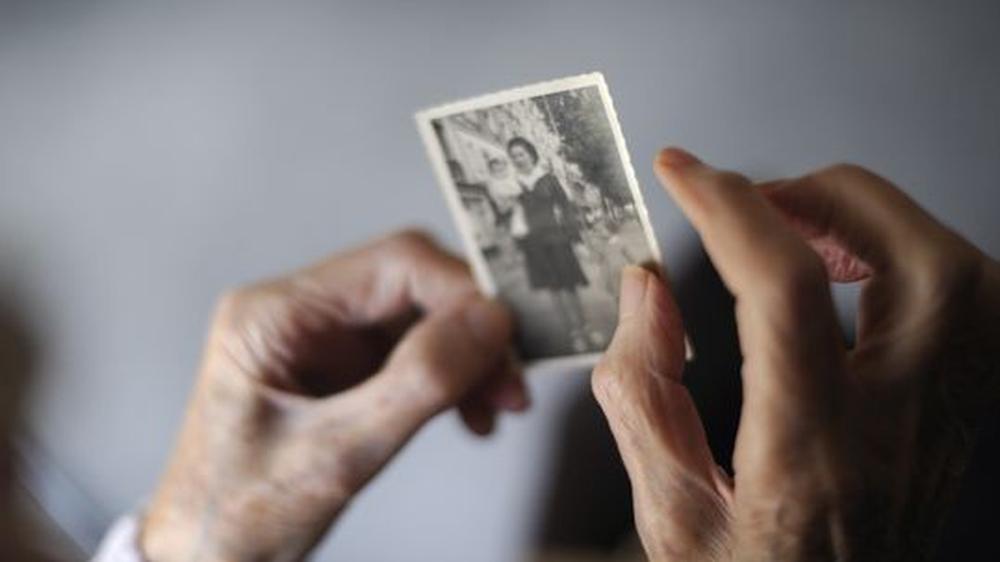 Eine Alzheimerpatientin betrachtet ein Foto von sich aus ihrer Jugend