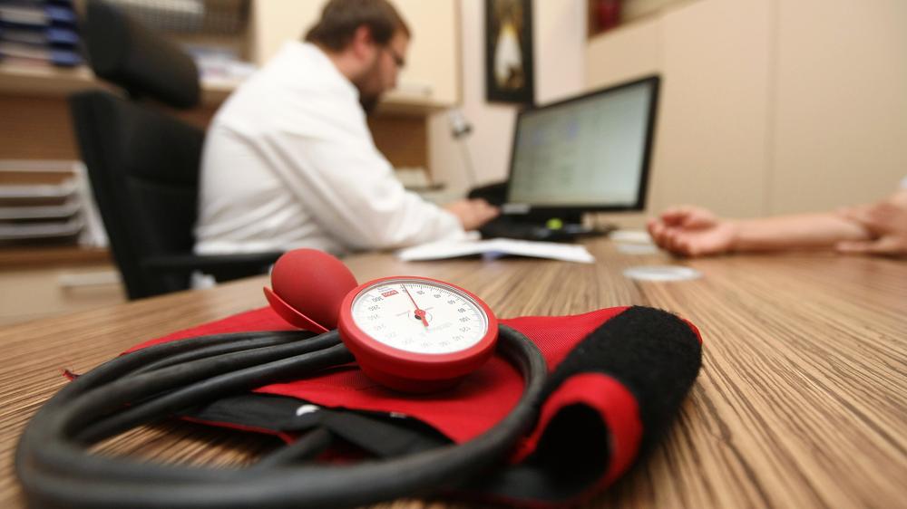 Krankenkasse: BERLIN, GERMANY - SEPTEMBER 05: A doctor speaks to a patient as a sphygmomanometer, or blood pressure meter, lies on his desk on September 5, 2012 in Berlin, Germany. 