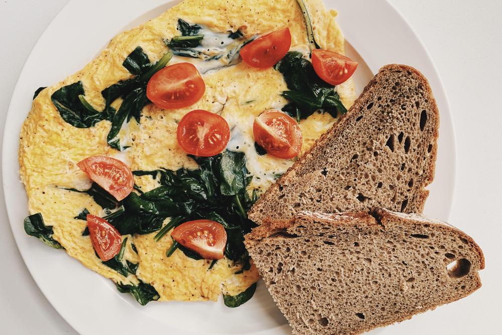 Sättigendes Frühstück: Das macht bestimmt satt: Omelett mit Babyspinat und Tomaten und Brot