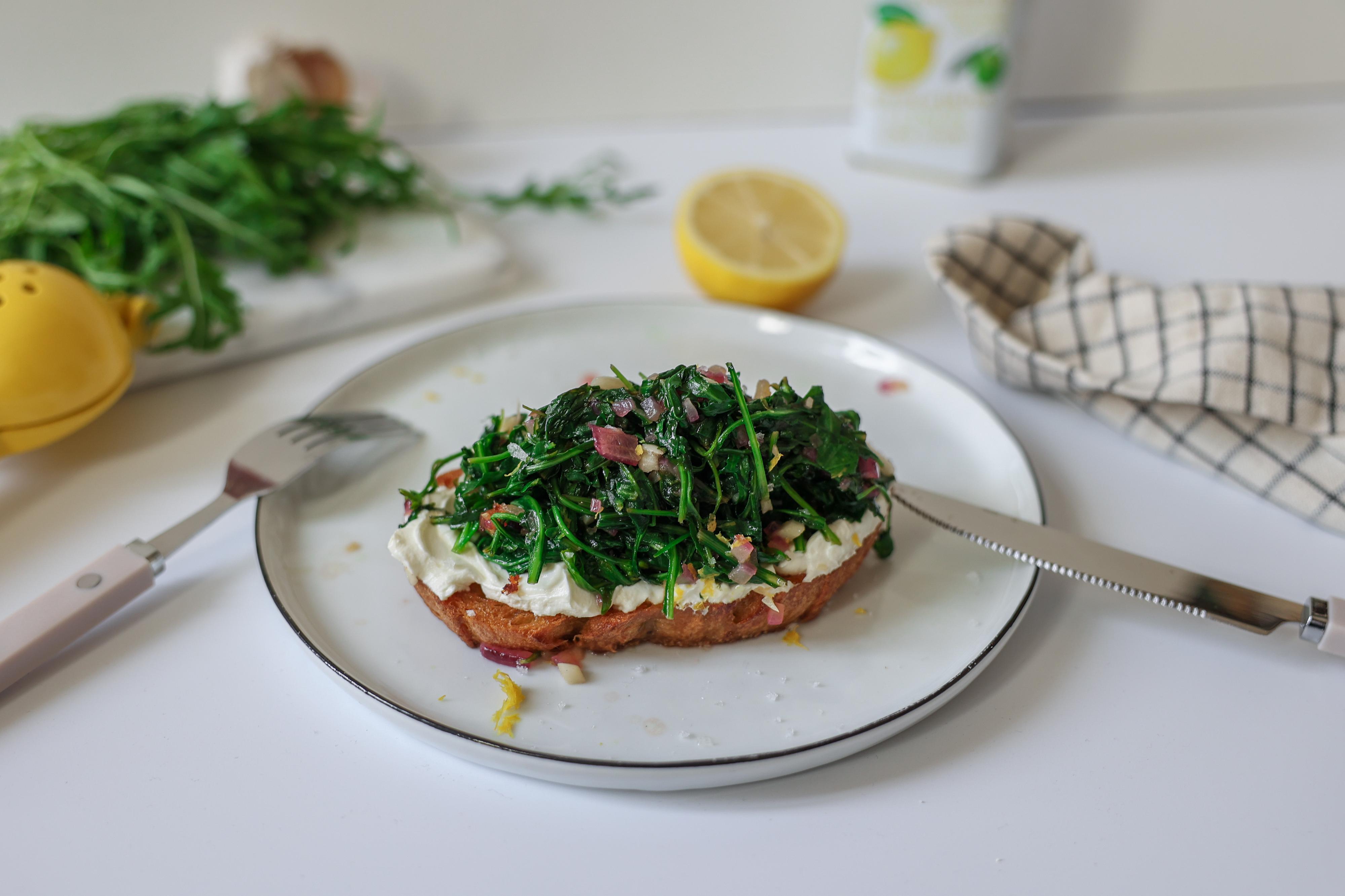 Gerösteter Rucola: Warmer Rucola auf einer gerösteten Brotscheibe mit Frischkäse bestrichen